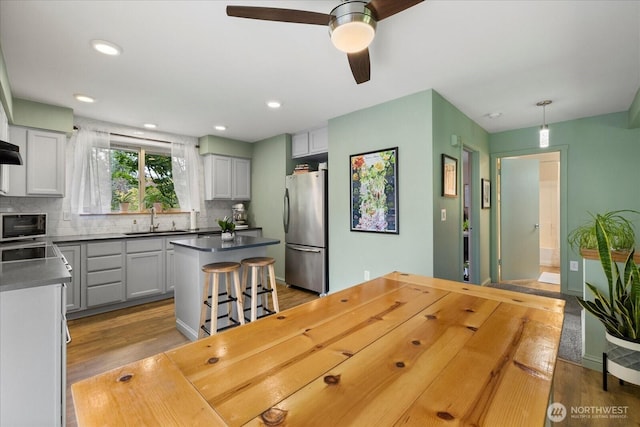 35632 158th St SE, Sultan, WA 98294 - kitchen featuring freestanding refrigerator, a kitchen island, wood finished floors, decorative backsplash, and a ceiling fan