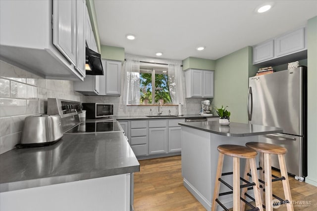 35632 158th St SE, Sultan, WA 98294 - kitchen featuring freestanding refrigerator, dark countertops, wall chimney range hood, light wood-style flooring, and decorative backsplash