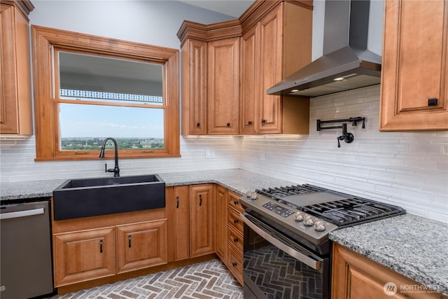 11801 Rd 5.6 NE, Moses Lake, WA 98837 - kitchen featuring wall chimney range hood, stainless steel appliances, light stone countertops, brown cabinetry, and brick patterned flooring