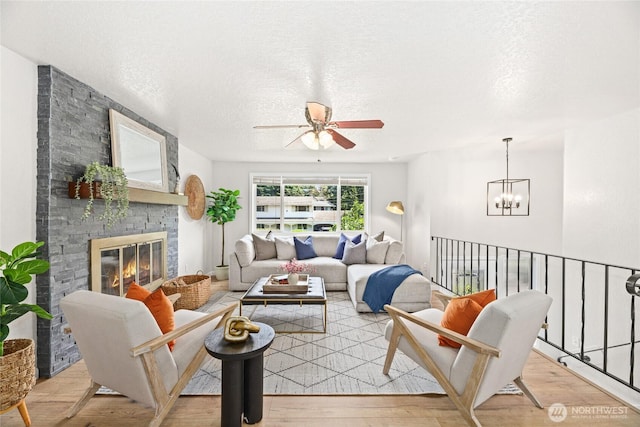 13045 28th Ave NE, Seattle, WA 98125 - living area with a ceiling fan, light wood-style floors, a chandelier, a fireplace, and a textured ceiling