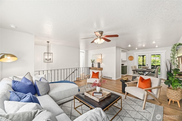 13045 28th Ave NE, Seattle, WA 98125 - living room featuring a chandelier, light wood-style flooring, a ceiling fan, and a textured ceiling
