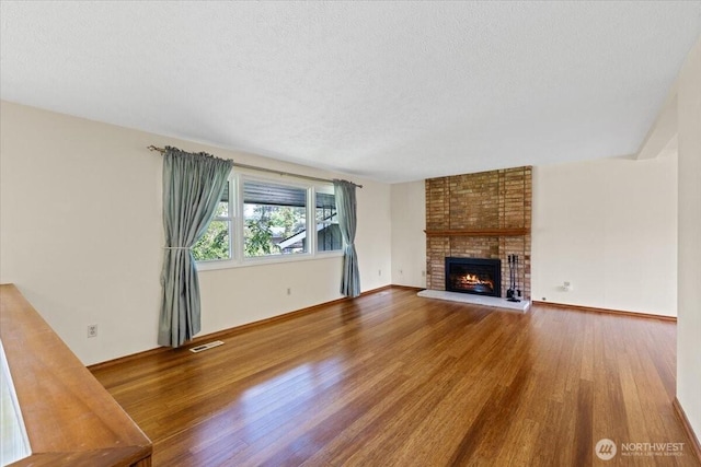 4128 S Lee St, Spokane, WA 99203 - unfurnished living room featuring wood finished floors, a textured ceiling, and a brick fireplace