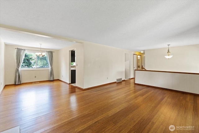 4128 S Lee St, Spokane, WA 99203 - unfurnished living room with a chandelier, hardwood / wood-style floors, and a textured ceiling