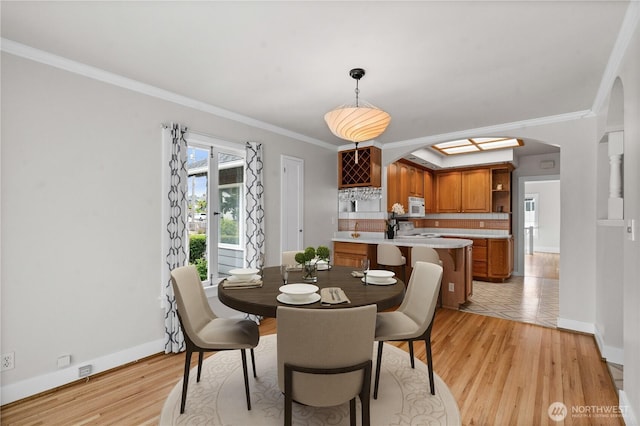 6903 Fauntleroy Way SW, Seattle, WA 98136 - dining area with arched walkways, crown molding, and light wood finished floors