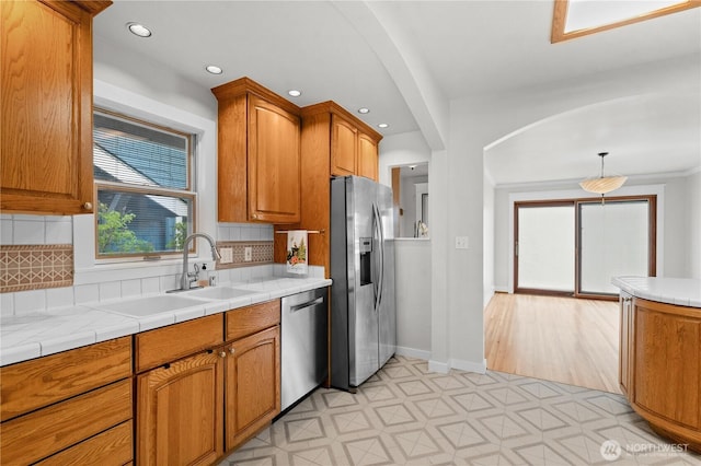 6903 Fauntleroy Way SW, Seattle, WA 98136 - kitchen featuring appliances with stainless steel finishes, arched walkways, light floors, backsplash, and brown cabinets
