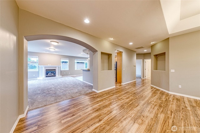 120 Petal Ln, Sequim, WA 98382 - unfurnished room with light wood-style floors, arched walkways, recessed lighting, and a glass covered fireplace