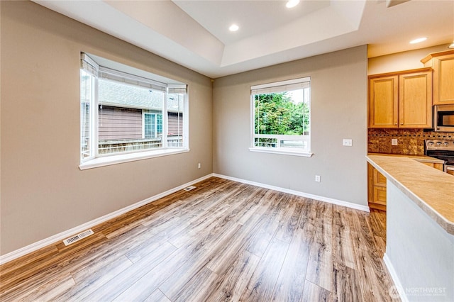 120 Petal Ln, Sequim, WA 98382 - kitchen with stainless steel appliances, light wood-style flooring, a tray ceiling, light countertops, and tasteful backsplash