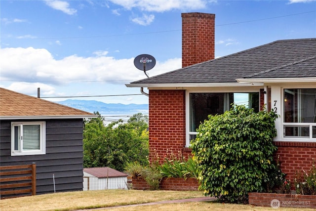 727 E 11th St, Port Angeles, WA 98362 - view of property exterior with brick siding, a chimney, a mountain view, and a shingled roof