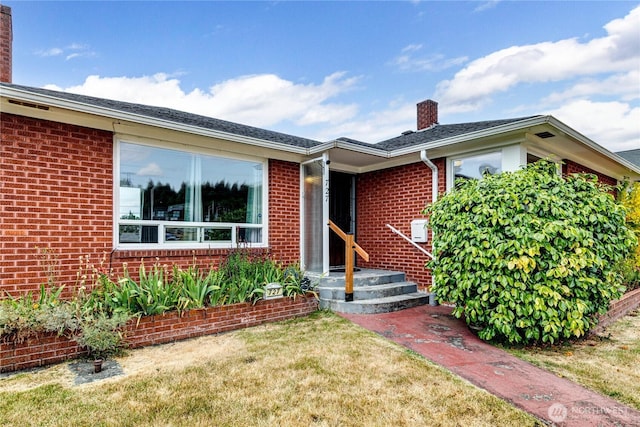 727 E 11th St, Port Angeles, WA 98362 - view of front facade featuring a chimney, brick siding, and a front lawn