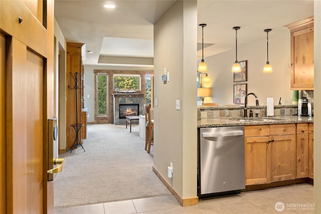 3770 Suncadia Trl Unit 309, Cle Elum, WA 98922 - kitchen with stainless steel dishwasher, light carpet, light stone countertops, a tiled fireplace, and hanging light fixtures
