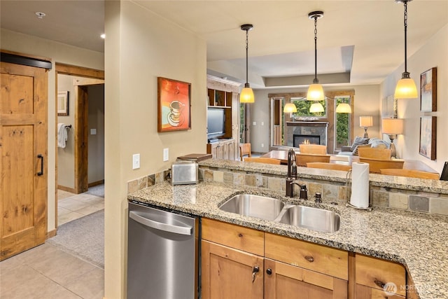 3770 Suncadia Trl Unit 309, Cle Elum, WA 98922 - kitchen featuring stainless steel dishwasher, light tile patterned floors, a tiled fireplace, a raised ceiling, and light stone countertops