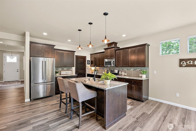 19537 207th Street Ct E, Orting, WA 98360 - kitchen with appliances with stainless steel finishes, dark brown cabinets, backsplash, healthy amount of natural light, and recessed lighting