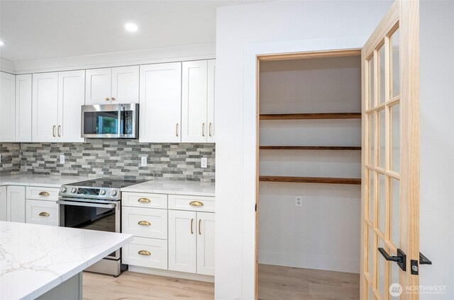 6203 119th St E, Puyallup, WA 98373 - kitchen with appliances with stainless steel finishes, light wood-style floors, tasteful backsplash, light stone countertops, and white cabinetry