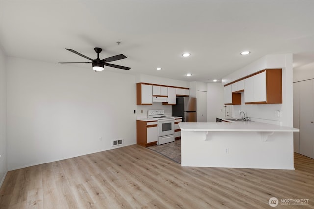 2255 Highview Ln W Unit D101, Bremerton, WA 98312 - kitchen with white range with electric cooktop, freestanding refrigerator, a peninsula, light wood finished floors, and light countertops