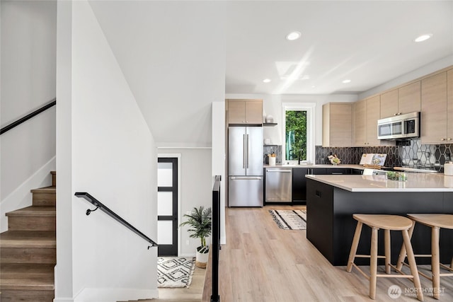 2817 Franklin Ave E Unit B, Seattle, WA 98102 - kitchen with appliances with stainless steel finishes, a breakfast bar area, light wood-style floors, light countertops, and tasteful backsplash