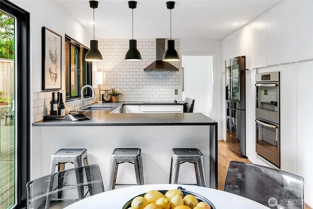 9101 SE 57th St, Mercer Island, WA 98040 - kitchen featuring wall chimney range hood, black appliances, dark countertops, backsplash, and a peninsula