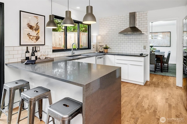 9101 SE 57th St, Mercer Island, WA 98040 - kitchen featuring wall chimney exhaust hood, a peninsula, a kitchen bar, dark countertops, and white cabinets