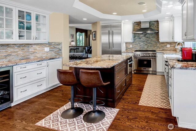 20821 NE 141st St, Woodinville, WA 98077 - kitchen with high end appliances, wall chimney exhaust hood, beverage cooler, white cabinetry, and recessed lighting