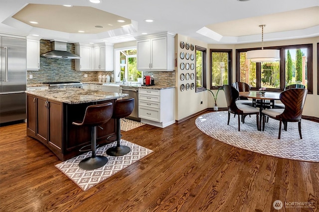 20821 NE 141st St, Woodinville, WA 98077 - kitchen featuring wall chimney range hood, a raised ceiling, appliances with stainless steel finishes, white cabinets, and tasteful backsplash
