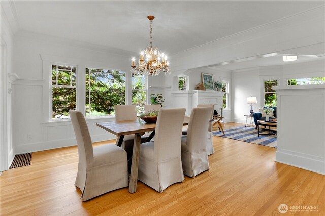 1523 4th Ave N, Seattle, WA 98109 - dining area featuring a chandelier, light wood-type flooring, healthy amount of natural light, ornamental molding, and a decorative wall