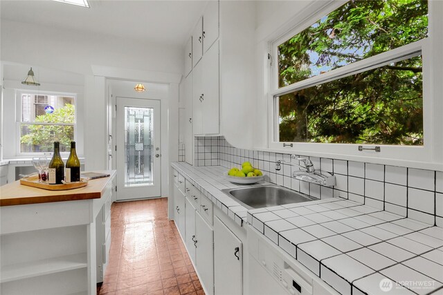 1523 4th Ave N, Seattle, WA 98109 - kitchen with tile counters, white cabinets, tasteful backsplash, open shelves, and white dishwasher