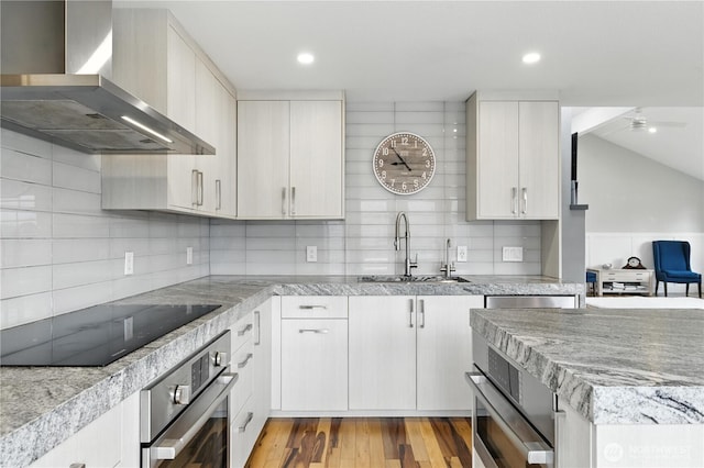 2500 171st Ave SE, Bellevue, WA 98008 - kitchen featuring wall chimney range hood, oven, black electric cooktop, decorative backsplash, and a ceiling fan