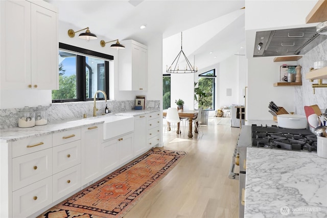 405 Bayside Rd, Bellingham, WA 98225 - kitchen with white cabinets, light wood-type flooring, tasteful backsplash, stainless steel gas range, and light stone counters
