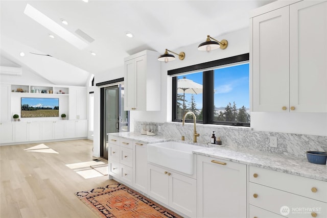 405 Bayside Rd, Bellingham, WA 98225 - kitchen with lofted ceiling, white cabinetry, light wood finished floors, light stone countertops, and recessed lighting