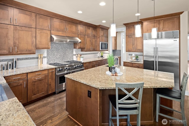 2507 101st Ln NE, Bellevue, WA 98004 - kitchen featuring built in appliances, extractor fan, dark wood-style floors, a kitchen island with sink, and decorative backsplash