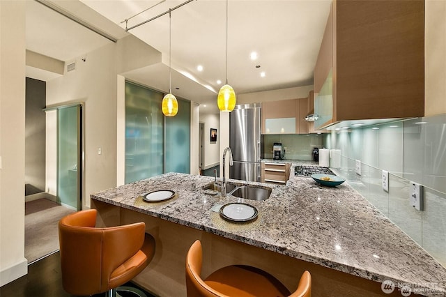 737 Olive Way Unit 3606, Seattle, WA 98101 - kitchen featuring light stone countertops, stainless steel refrigerator, a peninsula, backsplash, and decorative light fixtures