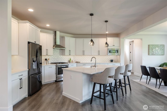 2035 S Fruitland, Puyallup, WA 98371 - kitchen featuring appliances with stainless steel finishes, wall chimney range hood, a breakfast bar, white cabinets, and dark wood finished floors