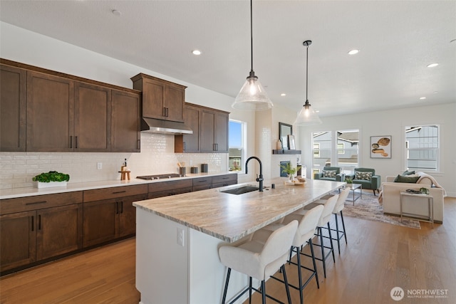 310 W Fir Loop, Washougal, WA 98671 - kitchen with under cabinet range hood, stainless steel gas cooktop, light wood-style floors, decorative backsplash, and plenty of natural light