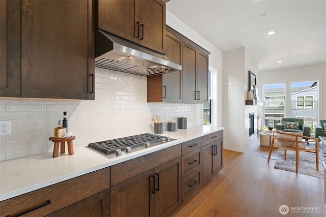 310 W Fir Loop, Washougal, WA 98671 - kitchen featuring ventilation hood, stainless steel gas cooktop, a fireplace, light wood-style flooring, and light countertops