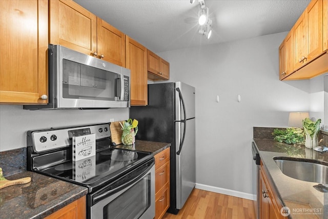 10831 NE 147th Ln Unit R202, Bothell, WA 98011 - kitchen featuring stainless steel appliances, light wood-style flooring, dark stone counters, brown cabinets, and a textured ceiling