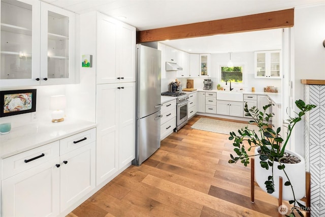10426 SW 112th St, Vashon, WA 98070 - kitchen with appliances with stainless steel finishes, under cabinet range hood, white cabinetry, light countertops, and glass insert cabinets