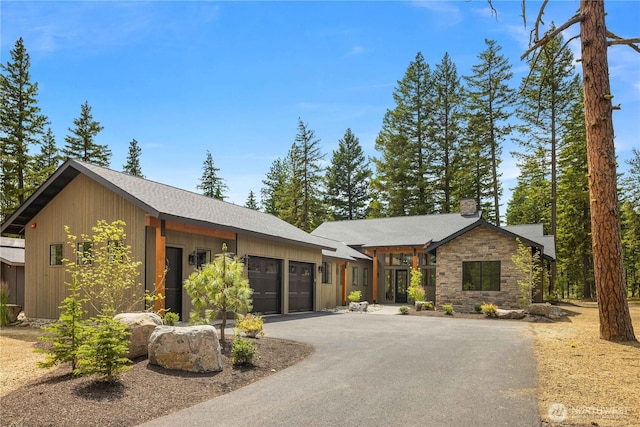 1950 Wanawish Loop, Cle Elum, WA 98922 - view of front of house with a garage, stone siding, asphalt driveway, roof with shingles, and a chimney