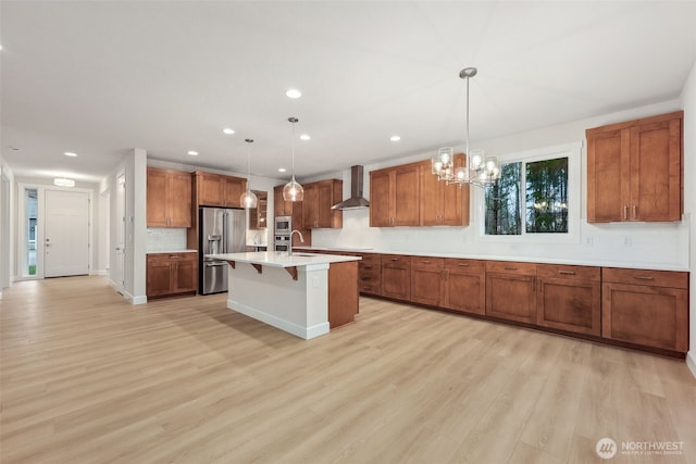 13600 100th St NE Unit 212, Lake Stevens, WA 98258 - kitchen featuring wall chimney range hood, appliances with stainless steel finishes, brown cabinetry, light wood-style flooring, and recessed lighting