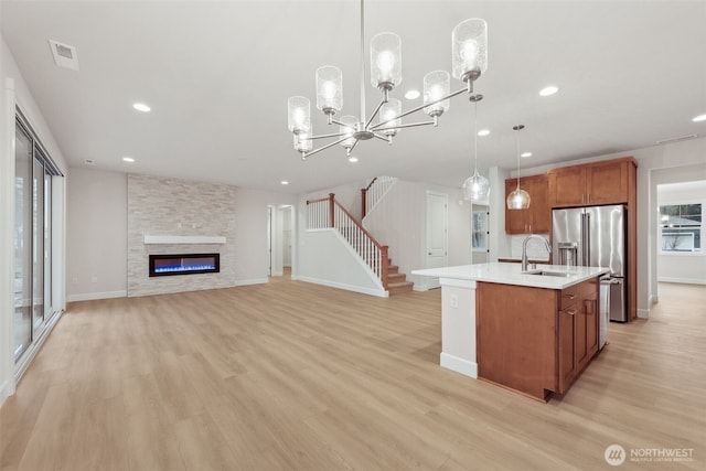 13600 100th St NE Unit 212, Lake Stevens, WA 98258 - kitchen featuring brown cabinetry, light wood-type flooring, light countertops, high end fridge, and a center island with sink