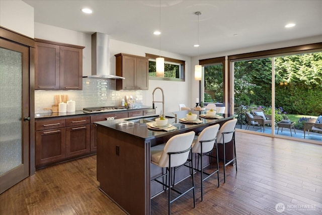 6555 125th Ave NE, Kirkland, WA 98033 - kitchen featuring wall chimney range hood, dark countertops, a kitchen breakfast bar, dark wood finished floors, and a kitchen island with sink