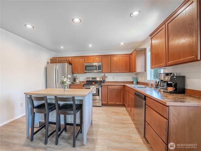 2135 Roper Ln, Wenatchee, WA 98801 - kitchen with appliances with stainless steel finishes, recessed lighting, light wood-style floors, a kitchen bar, and brown cabinets