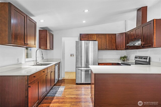 20102 119th St E, Sumner, WA 98390 - kitchen with appliances with stainless steel finishes, vaulted ceiling, under cabinet range hood, wood finished floors, and light countertops