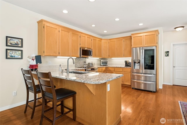 8206 66th Avenue Ct E, Puyallup, WA 98371 - kitchen with stainless steel appliances, a peninsula, wood finished floors, light stone countertops, and recessed lighting