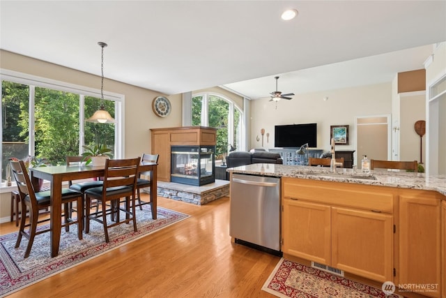 8206 66th Avenue Ct E, Puyallup, WA 98371 - kitchen with dishwasher, a multi sided fireplace, light wood-type flooring, a ceiling fan, and hanging light fixtures
