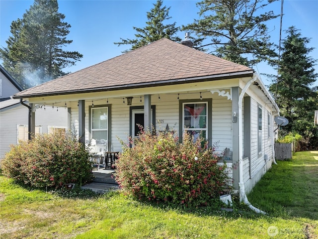 1205 49th St, Seaview, WA 98644 - view of front of house featuring covered porch, a front yard, a chimney, and a shingled roof
