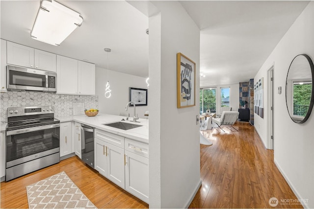 6347 137th Ave NE Unit 262, Redmond, WA 98052 - kitchen featuring appliances with stainless steel finishes, light countertops, white cabinets, tasteful backsplash, and light wood-style flooring