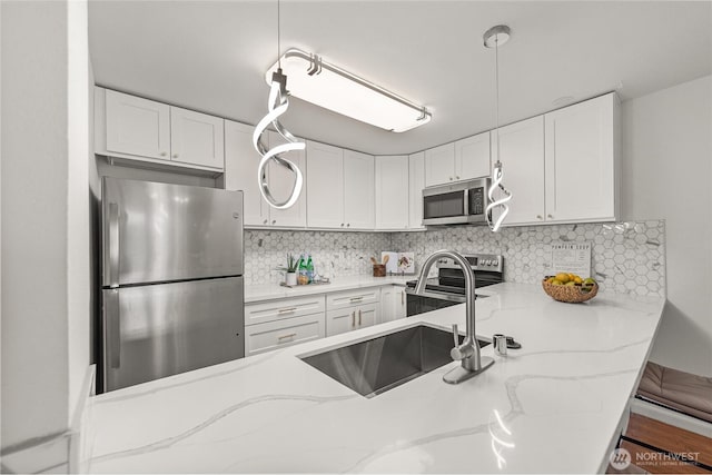 6347 137th Ave NE Unit 262, Redmond, WA 98052 - kitchen featuring appliances with stainless steel finishes, white cabinets, light stone counters, and tasteful backsplash