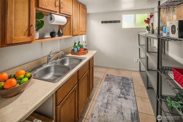 13316 30th Ave NE, Seattle, WA 98125 - kitchen with brown cabinetry, a textured wall, light countertops, light tile patterned floors, and a textured ceiling