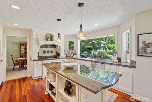 1800 SE 202nd Ave, Camas, WA 98607 - kitchen featuring stainless steel dishwasher, wood finished floors, white cabinets, black electric stovetop, and hanging light fixtures