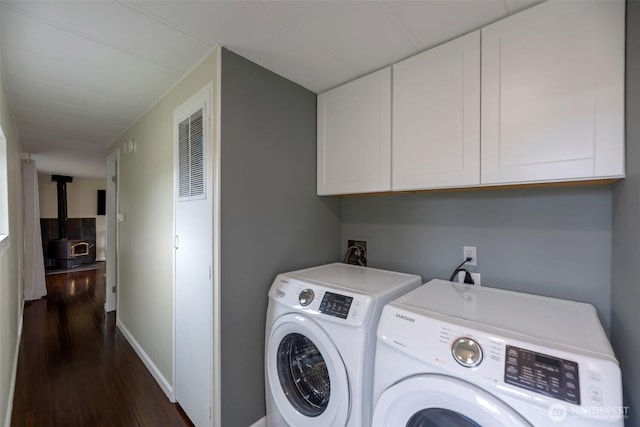 31108 3rd Ave Unit 330, Black Diamond, WA 98010 - laundry room featuring washer and clothes dryer, cabinet space, a wood stove, and dark wood-style flooring