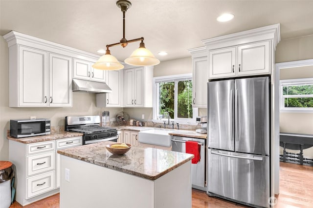 105 Shuksan St, Everson, WA 98247 - kitchen featuring appliances with stainless steel finishes, under cabinet range hood, a kitchen island, light stone countertops, and white cabinets